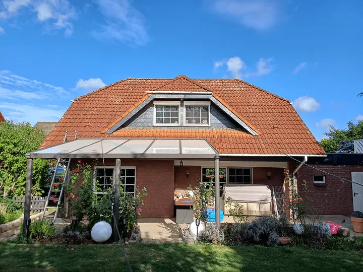 Haus mit verblasstem orangefarbenem Ziegeldach vor der Dachbeschichtung